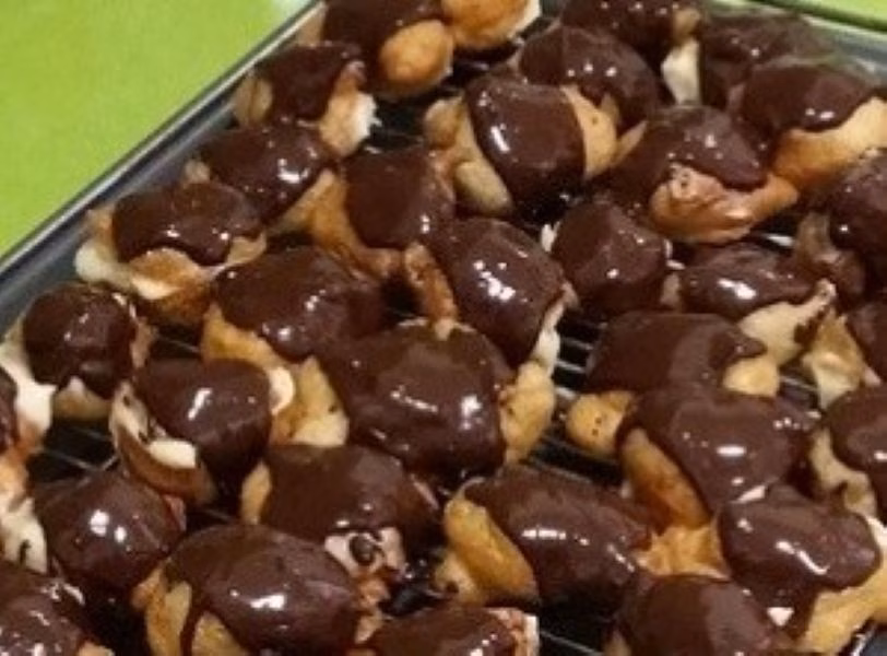 Buñuelos rellenos de crema y cubiertos de chocolate