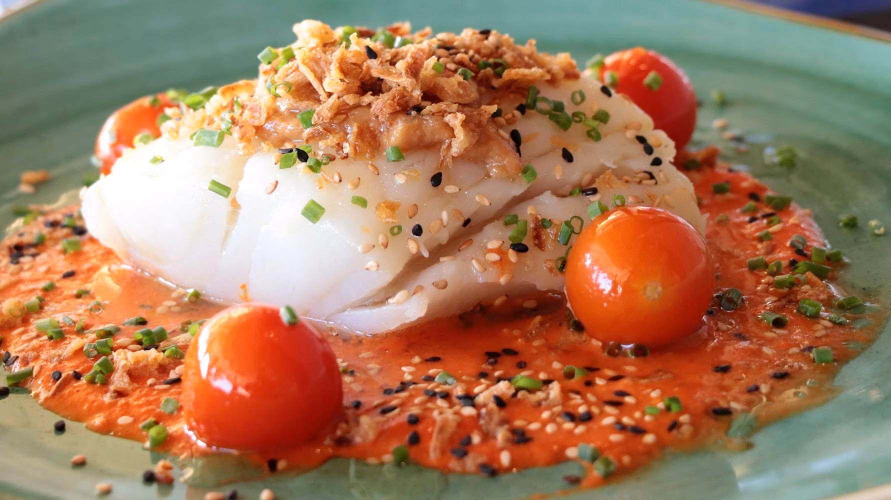 Bacalao confitado sobre salsa de piquillos, cebolla crujiente y cebollino