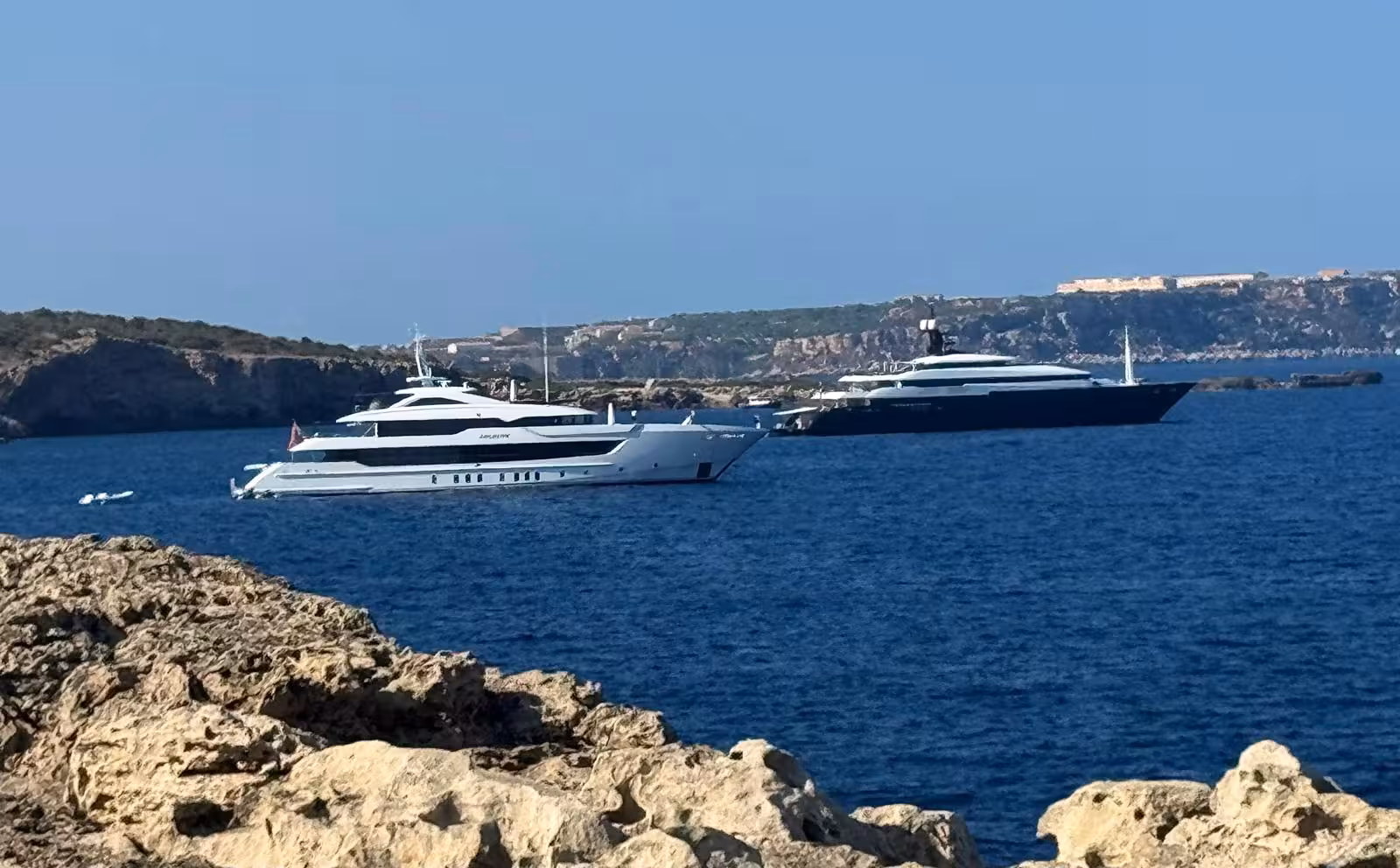 El yate Arbema (casco azul) navegando en la bocana del puerto de Maó. (Foto: TOLO MERCADAL)