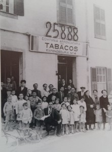 Fotografía 'de familia' en las afueras del estanco que vendió el Gordo en Ciutadella, con el 25.888 como fondo. Foto: Arxiu Històric Municipal de Ciutadella.