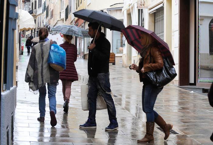 Gente con paraguas en el centro de Maó.