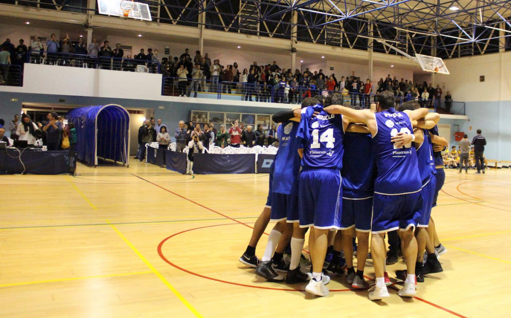 Piña de los jugadores tras un triunfo con el público aplaudiendo de fondo (Fotos: Bàsquet Menorca)