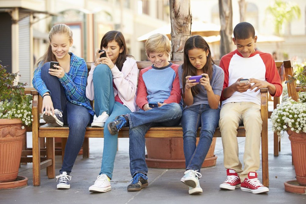 Niños consultando el teléfono móvil.