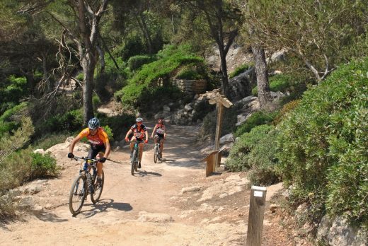 Excursionistas en bicicleta llegando a Cala Mitjana