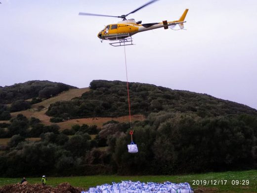 Un helicóptero trabaja en la restauración del empedrado de un tramo del Camí de Cavalls