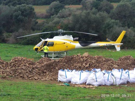 Un helicóptero trabaja en la restauración del empedrado de un tramo del Camí de Cavalls