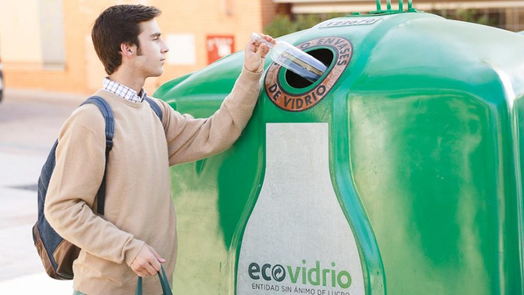 Un ciudadano lanzando un envase de vidrio al contenedor.