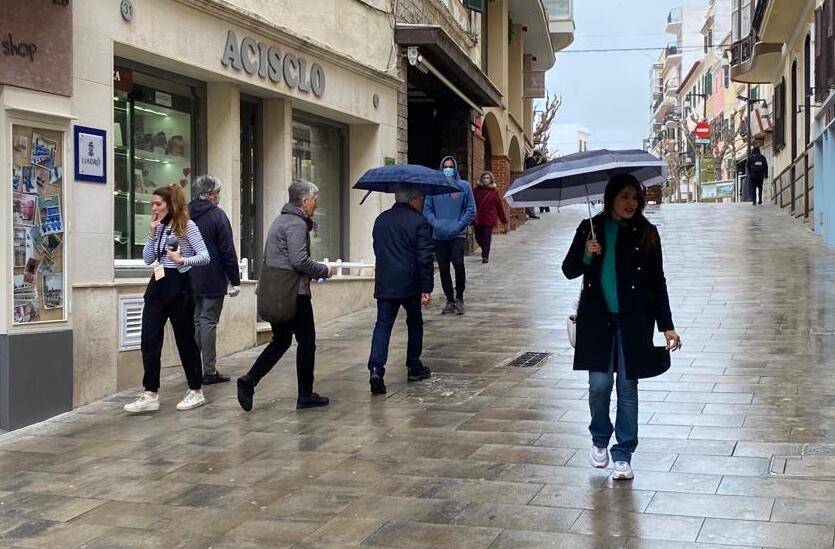 Gente protegida con paraguas en el centro de Maó esta mañana (Foto: Tolo Mercadal)