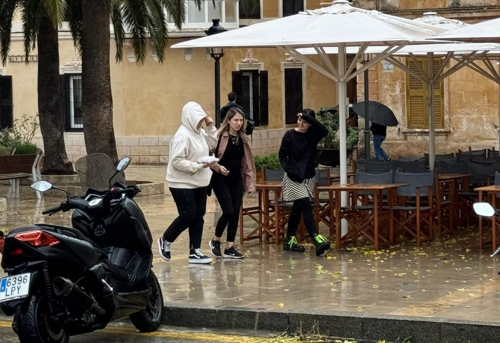 Gente protegiéndose de la lluvia (Foto: Tolo Mercadal)